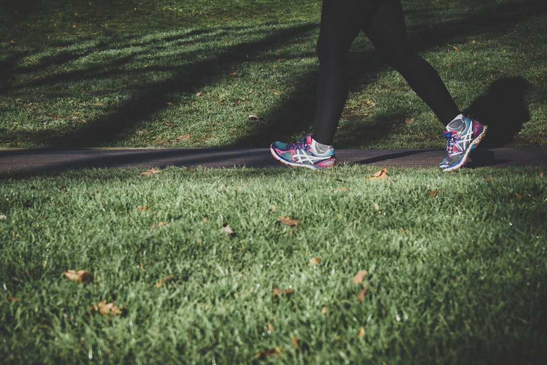 Photo by Arek Adeoye person walking on road between grass as she start her active journey