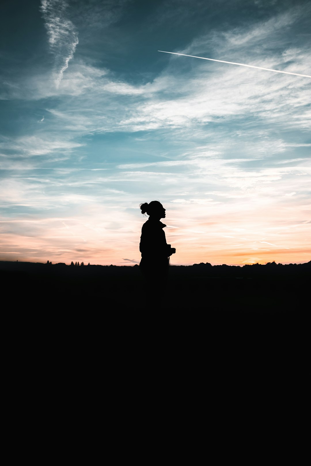 Photo by Ryan Klaus a silhouette of a person standing in front of a sunset