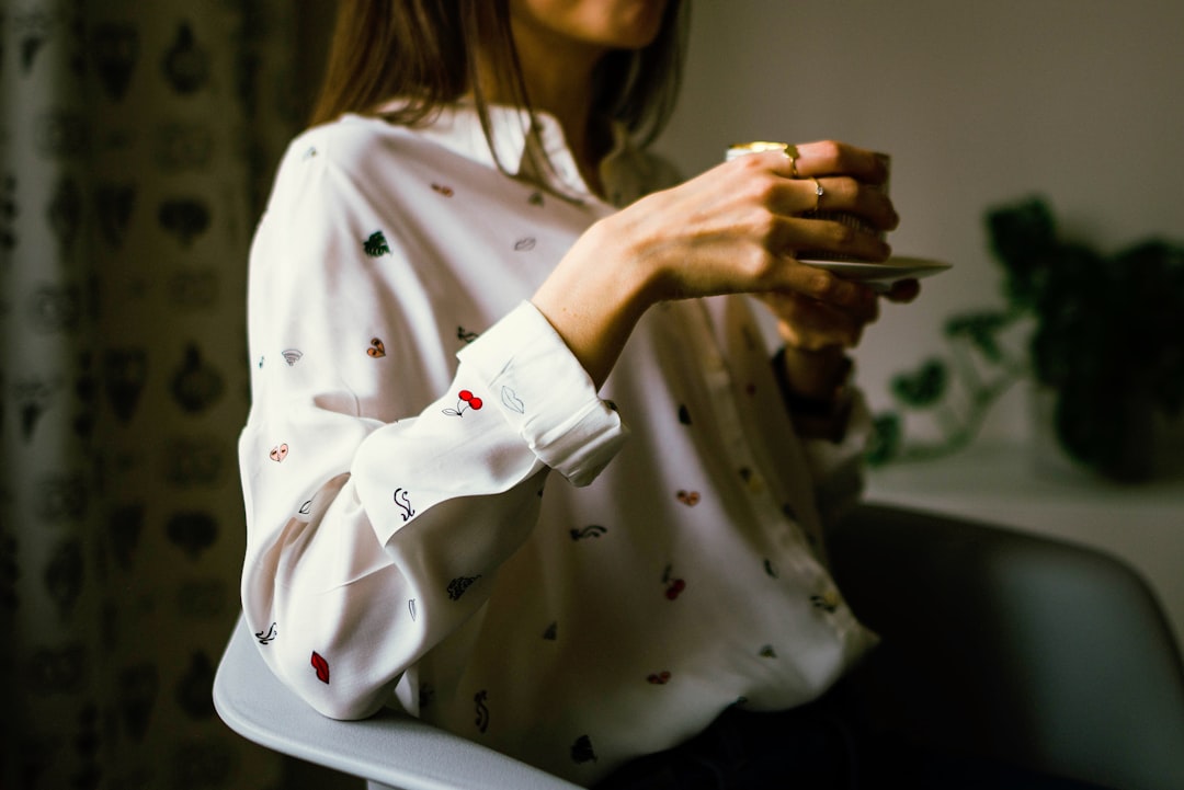 Photo by Jarek Ceborski woman in white long-sleeved collared shirt holding teacup